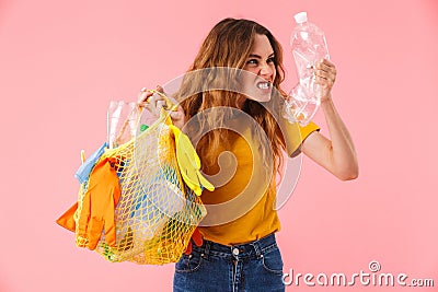 Photo of young furious woman holding bag with plastic waste and bottle Stock Photo