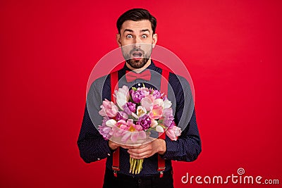 Photo of young handsome amazed surprised man hold bouquet receive birthday present isolated on red color background Stock Photo