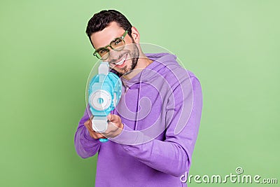 Photo of young handsome man happy positive smile play game water gun pool party isolated over green color background Stock Photo