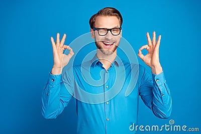 Photo of young man happy positive smile blink eye show okay alright great decision advert isolated over blue color Stock Photo