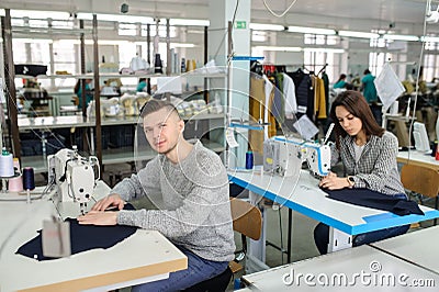 photo of a young man and other seamstresses sewing with sewing machine in a factory Stock Photo