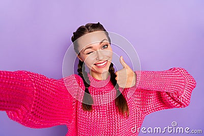 Photo of young pretty cheerful smiling girl wink blink eye showing thumb-up take selfie isolated on violet color Stock Photo