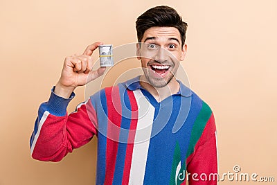 Photo of young shocked businessman holding twisted money demonstrate his sales income per one day isolated on beige Stock Photo