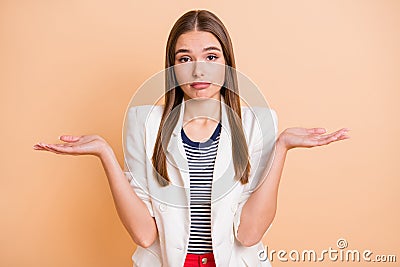 Photo of young unhappy uncertain unsure girl with long brown hair shrug shoulders isolated on beige color background Stock Photo