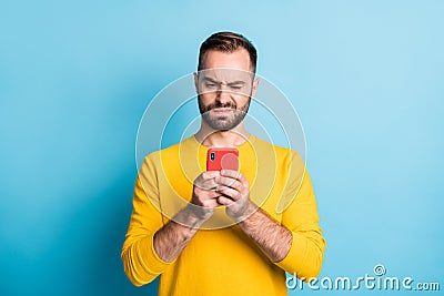 Photo of young unhappy upset sad unsure uncertain man see dislike bad comment in phone isolated on yellow color Stock Photo