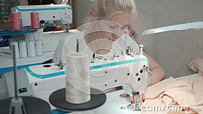 Photo of young woman sewing order on electric machine in workshop Stock Photo