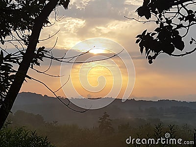Photograph of a blazing nuanced sky during a sunset above the contrast of a countryside landscape Stock Photo