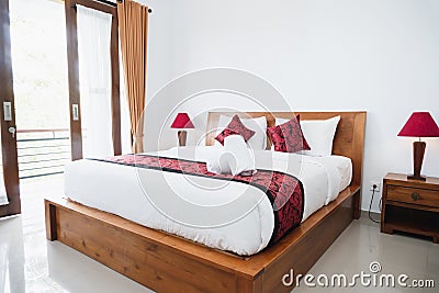 Photograph of bright white bedroom with wooden bed Stock Photo