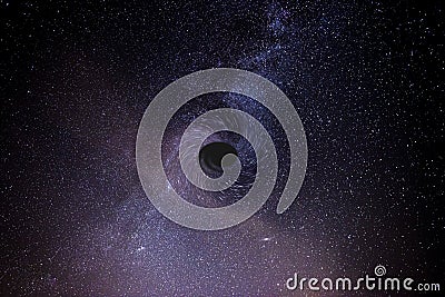 A photograph of the night sky, illustrating the presence and effect of a black hole on a nearby galaxy. Stock Photo