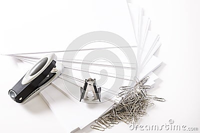 Photograph of some fan-shaped sheets of paper, a stapler, a staple extractor and some paper clips on a white background.The photo Stock Photo