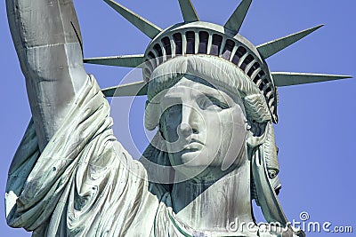 Photograph of the Statue of Liberty holding her torch on a sunny day in Manhattan, known as the lady of New York City. Editorial Stock Photo