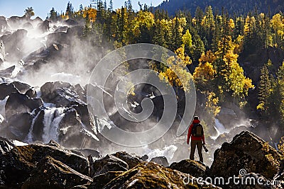 Photographer with backpack enjoying amazing waterfall Travel Lifestyle and success concept vacations into the wild Stock Photo