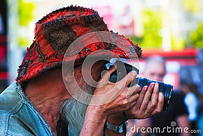 Photographer with beard and hat looking at the camera viewfinder Editorial Stock Photo