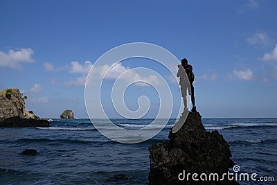 A photographer climbed onto the rocks on a beach to capture photos of Koka& x27;s beach landscape, Flores, Indonesia Stock Photo