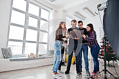 Photographer explaining about the shot to his team in the studio and looking on laptop. Talking to his assistants holding a camera Stock Photo