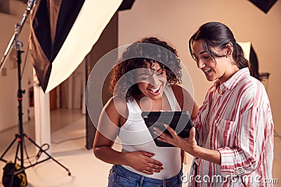 Photographer With Female Client Editing Images From Portrait Photo Shoot On Digital Tablet Stock Photo