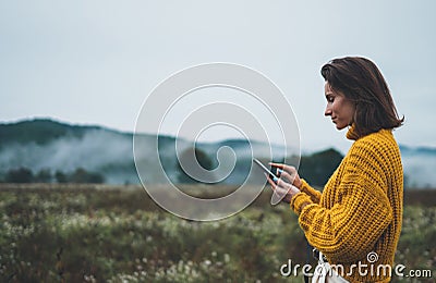 Photographer girl hold in hands mobile phone typing message on smartphone on background autumn froggy mountain, internet online Stock Photo