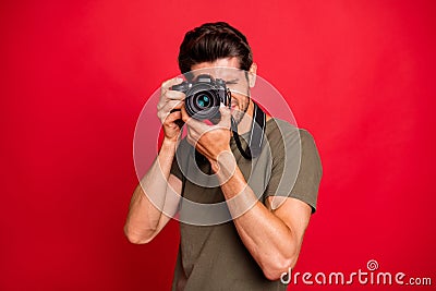 Photographer guy with photo digicam making pictures wear casual grey t-shirt isolated on red background Stock Photo