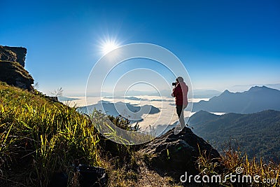 Photographer hand holding camera and standing on top of the rock in nature. Travel concept. Stock Photo