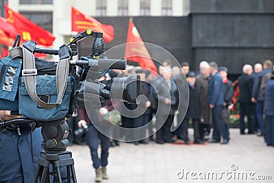 A photographer with a large professional camera looks through the viewfinder and takes a video Editorial Stock Photo