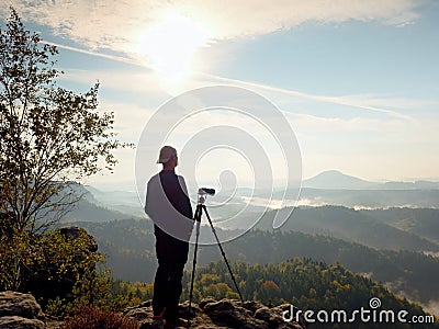 Photographer looks into the landscape and listen the silence. Man prepare camera to takes photos Stock Photo