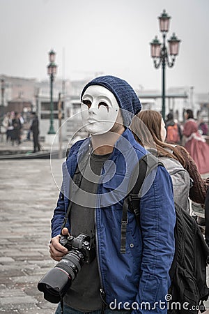 A photographer with a professional camera in mask with Venetian lamppost at background at St Mark's Square Editorial Stock Photo