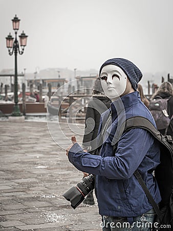 A photographer with a professional camera in mask with Venetian lamppost at background at St Mark's Square Editorial Stock Photo