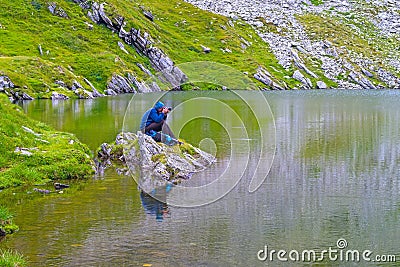 Photographer on a rock on a lake Stock Photo