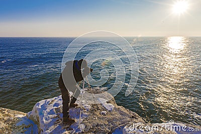 Photographer on the rocks taking landscape pictures Stock Photo