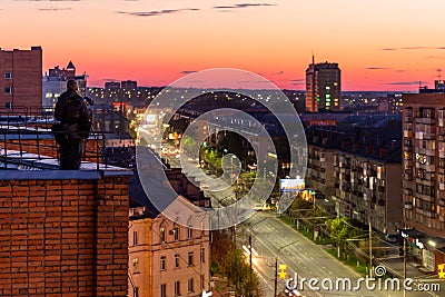 Photographer shooting night sity from edge of red brick condominium roof Stock Photo