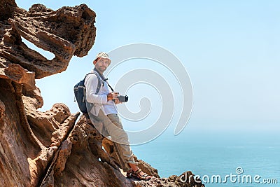 Photographer sits on a rock while traveling, Hormuz Island, Iran Stock Photo