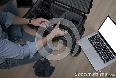 Photographer sitting on floor and putting camera accessories in special bag. Stock Photo