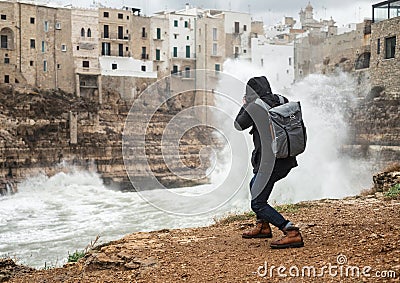 Photographer taking picture of a stormy sea in Polignano a Mare, Italy Stock Photo