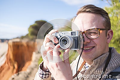 A photographer taking pictures of cliffs and ocean during sunny Stock Photo