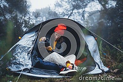 Photographer tourist traveler take photo on camera in camp tent in foggy rain forest, hiker woman shooting mist nature trip Stock Photo