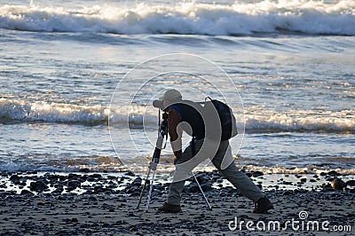 Photographer at water`s edge on Coastal Beach Editorial Stock Photo