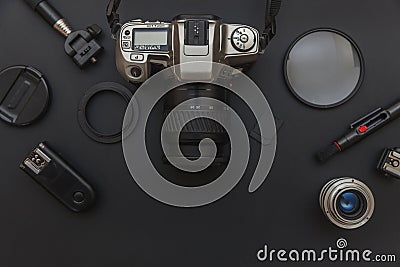 Photographer workplace with dslr camera system, camera cleaning kit, lens and camera accessory on dark black table background. Stock Photo