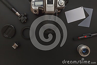 Photographer workplace with dslr camera system, camera cleaning kit, lens and camera accessory on dark black table background. Stock Photo