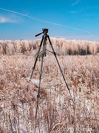 A photographers tripod against the backdrop of a winter landscape Stock Photo