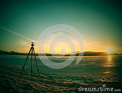 Photographers tripod ready to takes picture of frozen river Stock Photo