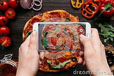 Photographing food. Hands taking picture of delicious pizza with smartphone Stock Photo