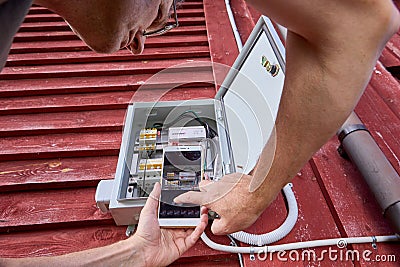 Consumer takes photo of readings of electricity meter in outdoor electrical panel using cell phone. Stock Photo
