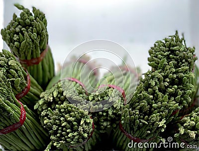 a photography of a bunch of asparagus in a glass container, broccoli and asparagus are in a bowl on a table Stock Photo
