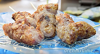 a photography of a plate of food with meat on a stick, there are several skewered meats on a blue plate Stock Photo