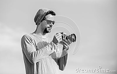 Photojournalist concept. Guy photographer outdoors sky background. Hipster reporter taking photo. Manual settings Stock Photo