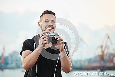 Photojournalist likes his work. Portrait of happy pleased handsome photographer smiling broadly while looking aside and Stock Photo