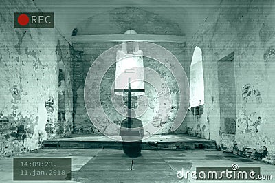 A Photoshop of a CCTV image of a hooded ghost kneeling next to a cross in a disused church. Stock Photo