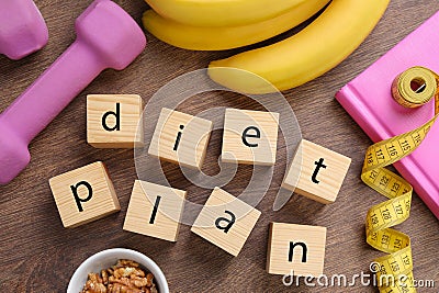 Phrase Diet Plan made of cubes, fitness items and products on wooden table, flat lay. Weight loss concept Stock Photo