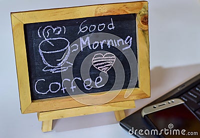 Phrase Good Morning coffee written on a chalkboard on it and smartphone, laptop Stock Photo