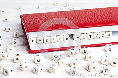 Phrase Hacker attack written in wooden blocks in red notebook on Stock Photo